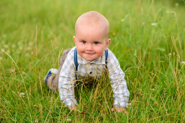Маленький однорічний хлопчик у зеленій траві
. - Фото, зображення