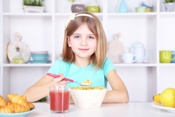 Beautiful little girl eating breakfast in kitchen at home - Foto, Bild