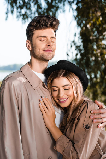 man with closed eyes hugging woman in hat outside - Fotografie, Obrázek
