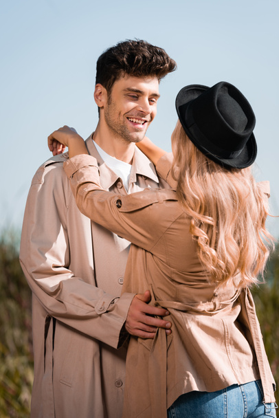 donna bionda in cappello nero abbracciando l'uomo in trench  - Foto, immagini