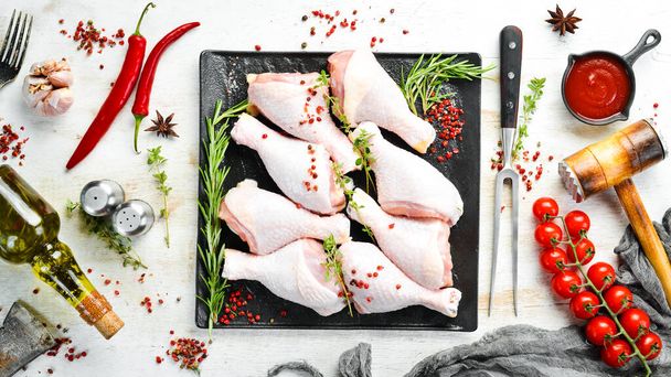 Raw chicken drumsticks with spices on a white wooden background. Meat. Top view. Rustic style. - Foto, Imagem