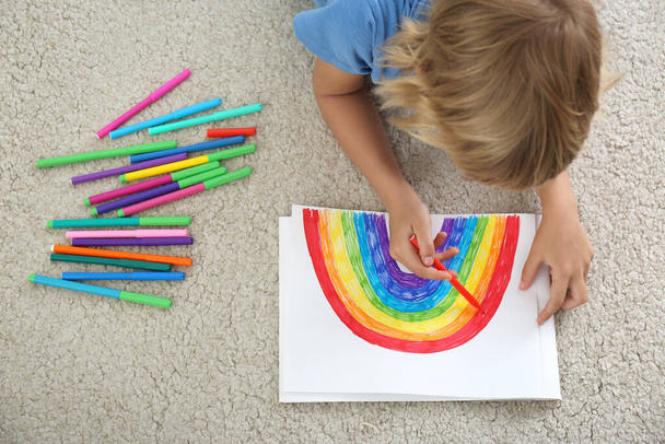 Little boy drawing rainbow on floor indoors, above view. Stay at home concept - Fotografie, Obrázek