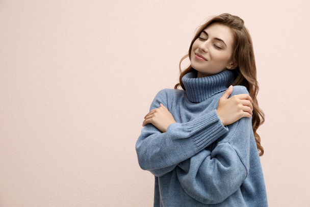 Beautiful young woman wearing warm blue sweater on light pink background. Space for text - Valokuva, kuva