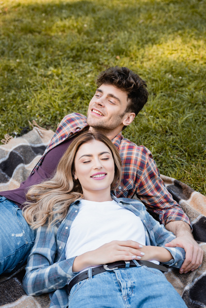 man and woman in plaid shirts lying on blanket  - 写真・画像