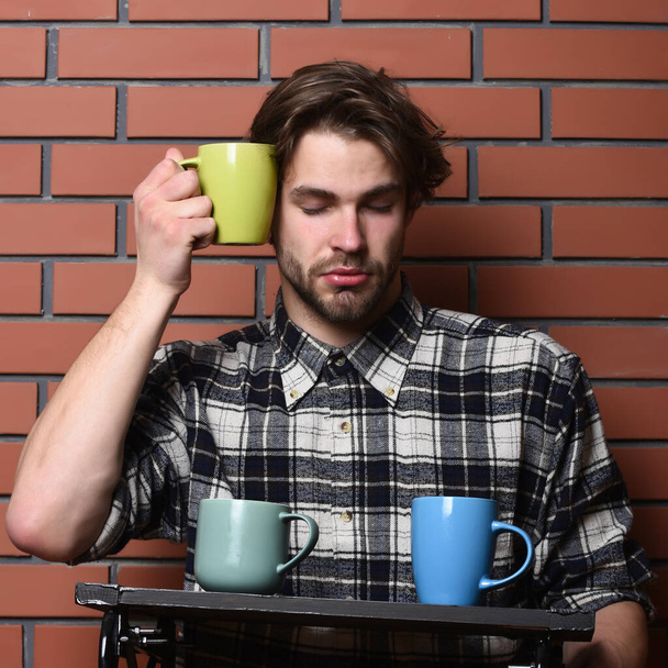 handsome guy holding cups on brick wall background - Foto, afbeelding