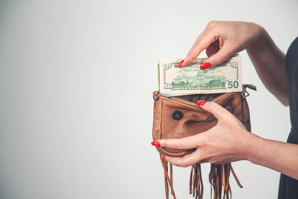 Mladá žena vytáhne dolarové bankovky peníze z hnědé peněženky tašky - Fotografie, Obrázek