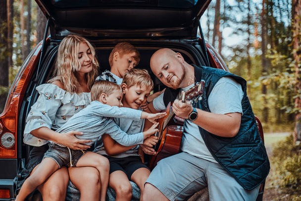 Wife and husband with their children and car in forest - Foto, Imagem