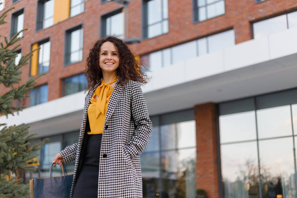 Smiling business woman with curly hair portrait outdoors at the modern building sunset as background. - Foto, afbeelding