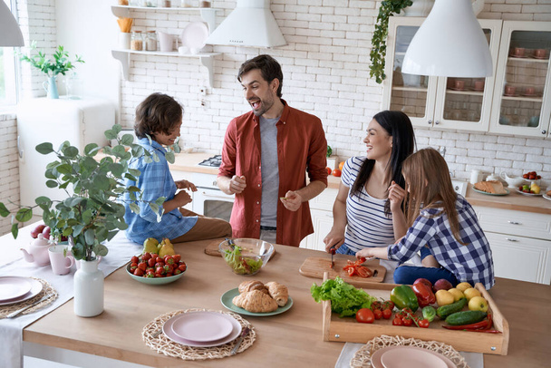 Cuisiner avec les parents. Belle belle famille préparant une salade, cuisiner ensemble dans la cuisine moderne à la maison - Photo, image
