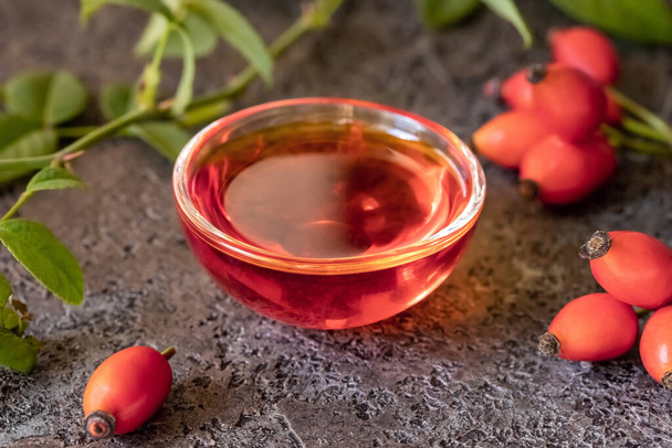 Butelka różanego oleju z nasion biodra ze świeżymi jagodami - Zdjęcie, obraz