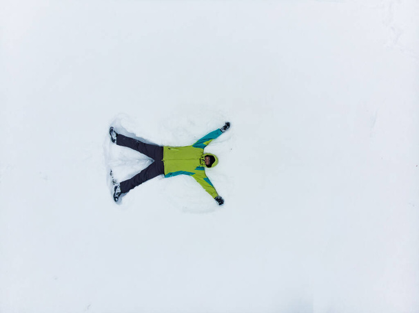 雪の天使のコピースペースを作る男のオーバーヘッドビュー - 写真・画像