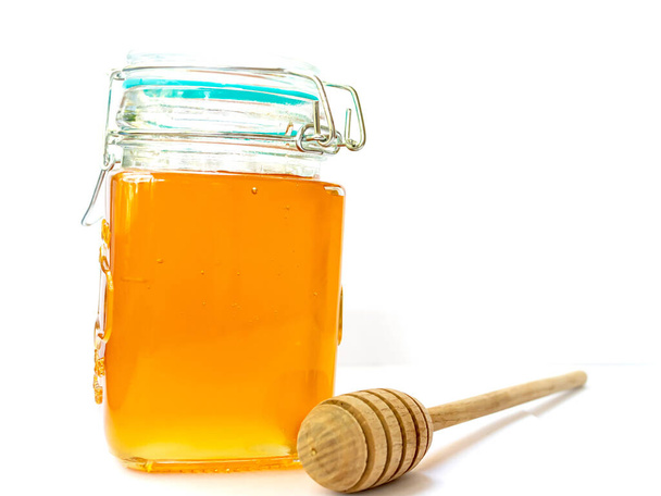 Üveg üveg virágos arany méz fedéllel fa méz stick helyet a szöveg számára - Fotó, kép