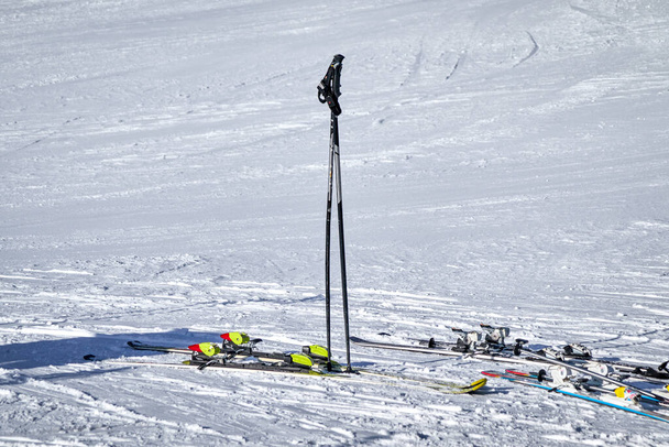 Pólos de esqui em pé na neve branca e alguns esquis coloridos diferentes estão ao lado deles - Foto, Imagem