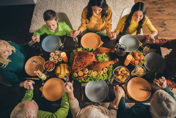 Top above high angle view of nice attractive calm peaceful big full family sitting around served table praying grace harvest November at modern loft industrial interior house indoors - Fotografie, Obrázek