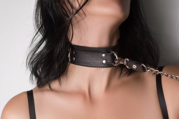 The young woman is wearing a black leather collar. Conceptual BDSM photo. - Foto, Imagem