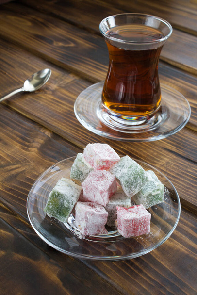 Türkische Süßigkeiten und Tee auf dem braunen Holztisch in Großaufnahme - Foto, Bild