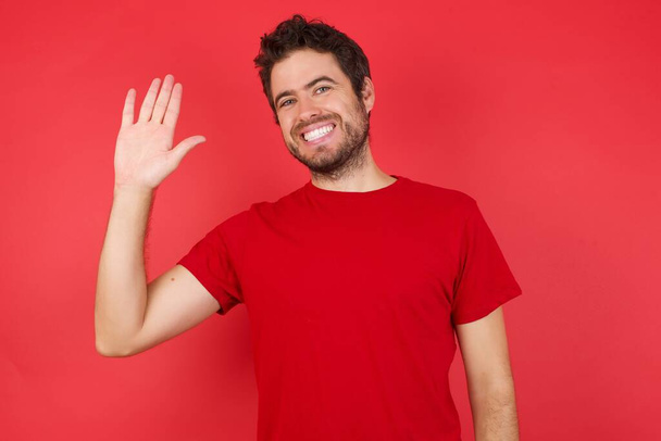 happy man in studio, Waiving saying hello happy and smiling, friendly welcome gesture. - Foto, imagen