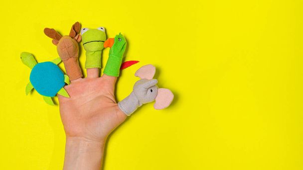 Doigts jouets en tissu sur la main sur une bannière de fond jaune avec une place pour le texte. Théâtre des doigts - Photo, image