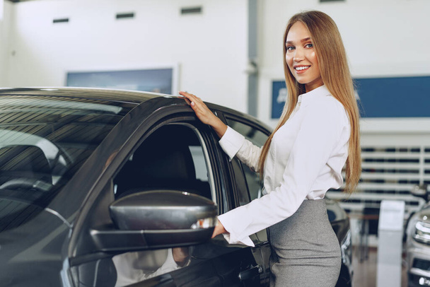 Beautiful young woman touching her new car with pleasure - Фото, зображення