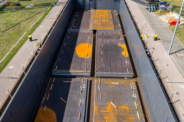 Barcaza llena de láminas de metal grueso, que fluye en la esclusa del río, vista superior de las bodegas de carga del barco. - Foto, Imagen