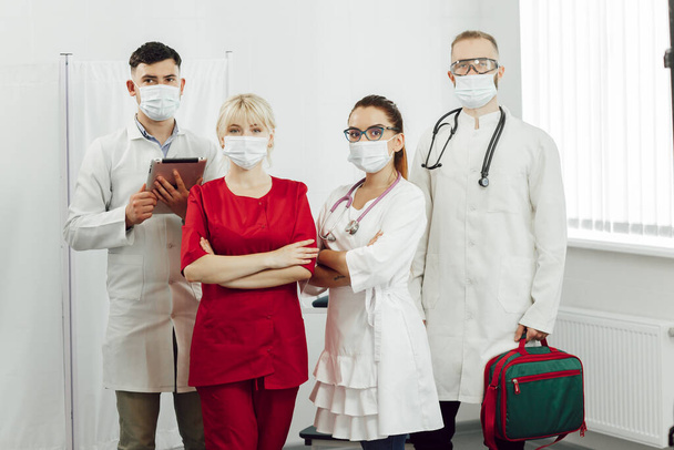 Retrato de médicos jóvenes de pie en una fila. Trabajo de los médicos durante la cuarentena del coronavirus - Foto, Imagen