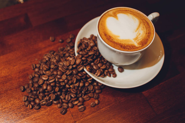 A cup of cappuccino with coffee bean as background. - Photo, image