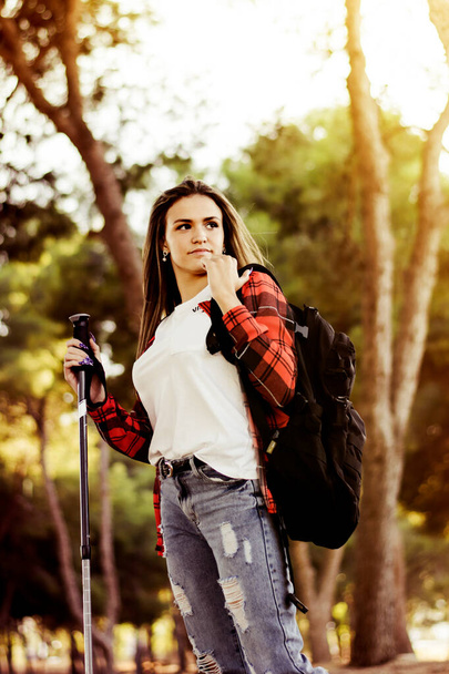 Jeune femme marchant dans la forêt avec des bâtons de randonnée - Photo, image