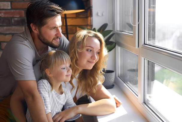happy young family looking through the window at home - Photo, Image