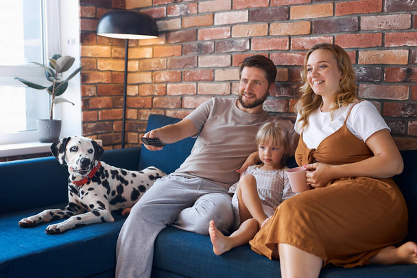 attractive happy family with dog watch tv in living room - Фото, изображение