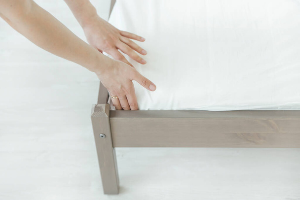 Žena dává povlečení nebo podložku matrace na postel nebo odkládá na úklid - Fotografie, Obrázek