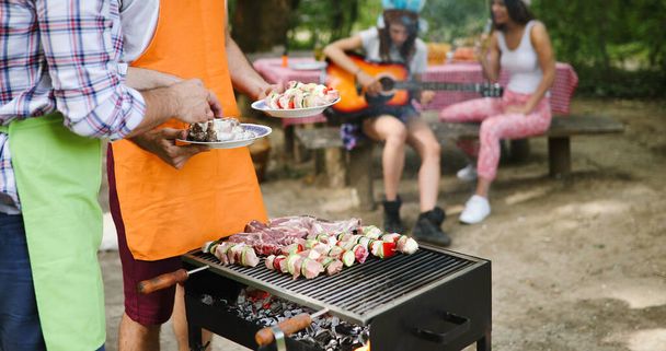 Friends having a barbecue party and having fun together in nature - 写真・画像