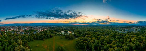 ミュンヘン、バイエルン、有名なドイツの都市の早朝の夜明けの色を持つ人気のある公園である英語の庭で美しい日の出のパノラマの航空. - 写真・画像