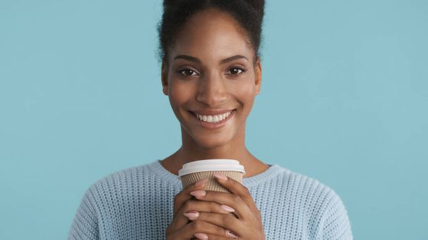 美しいですアフリカ系アメリカ人の女の子の肖像とともにコーヒー喜んで色鮮やかな背景上のカメラで見に行く - 写真・画像