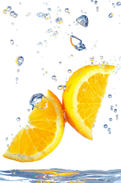 Rebanada de naranja salpicando en el agua
 - Foto, Imagen