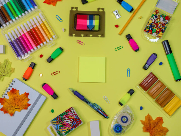 School stationery set lies scattered on a yellow paper background, top view close-up. - Photo, Image