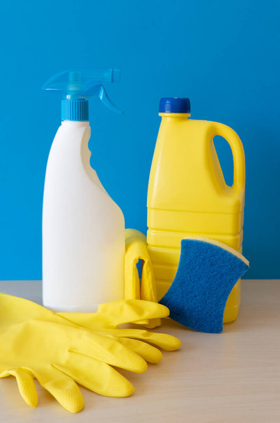 Cleaning products on wooden table and blue background. Front view. Vertical composition. - Фото, зображення