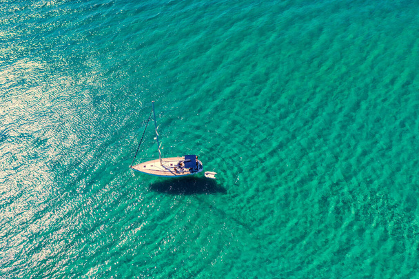 Jacht ankeren in kristalhelder turquoise water voor het tropische eiland, alternatieve levensstijl, wonen op een boot. Luchtfoto van jacht voor anker op turquoise water, waaruit luxe, rijkdom. - Foto, afbeelding
