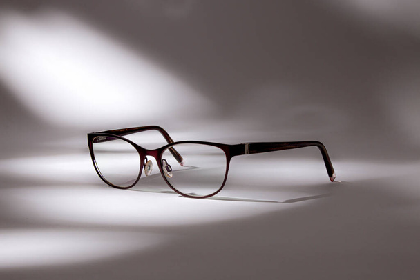 Дизайнер збільшуючи окуляри на білому тлі з фактурним світлом, який створює фігури з елегантними тінями
 - Фото, зображення