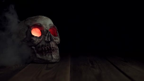 Un cráneo con brillantes ojos rojos que emiten humo aislado sobre un fondo negro - Metraje, vídeo
