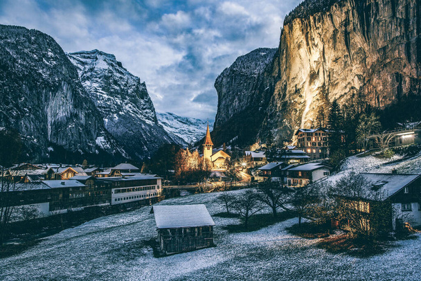 increíble pueblo alpino turístico por la noche en invierno con la famosa iglesia y la cascada de Staubbach Lauterbrunnen Suiza Europa - Foto, Imagen