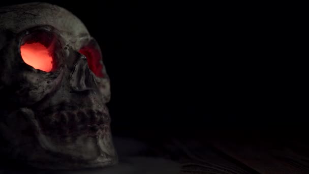 Cráneo con brillantes ojos rojos que emiten humo aislado sobre un fondo negro - Metraje, vídeo