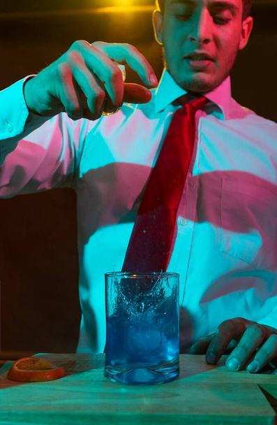 Barman preparing alcoholic drink with a cocktail shaker at the bar with some glasses of liqueur.  - Foto, imagen