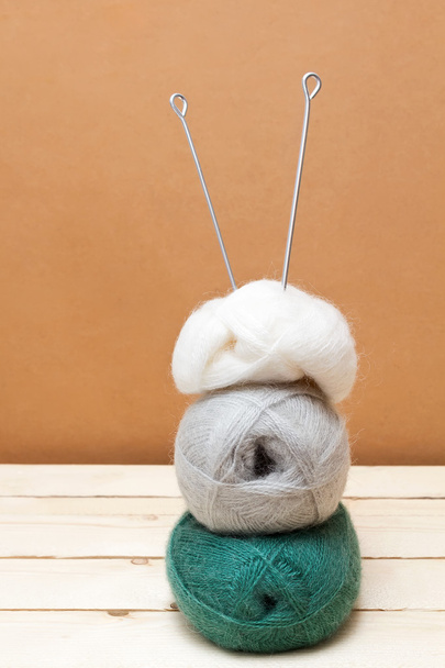 Knitting needles and balls of wool on a wooden table - Photo, image