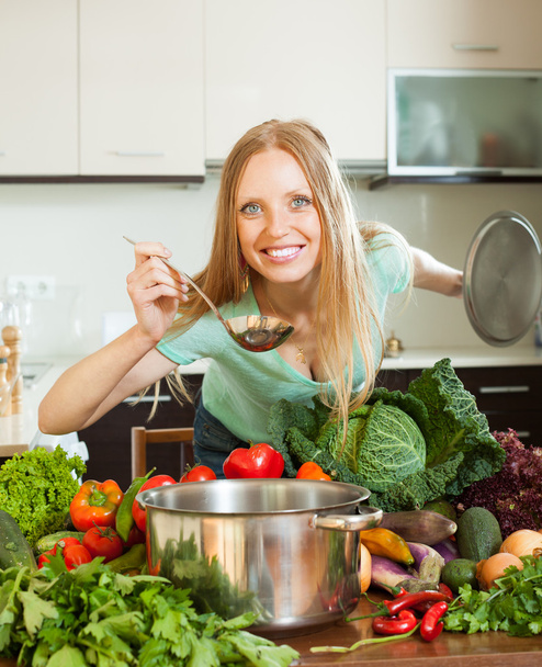 mujer positiva cocinando con cucharón de verduras crudas
 - Foto, Imagen