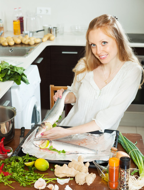 Γυναίκα ευτυχισμένη μαγείρεμα των ψαριών με λεμόνι στο φύλλο παν - Φωτογραφία, εικόνα