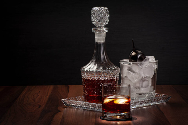 ront pohled na sklenici whisky s lahví a kbelíkem ledu na tmavém pozadí - Fotografie, Obrázek