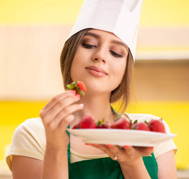 Nuori nainen kokki syö mansikoita - Valokuva, kuva