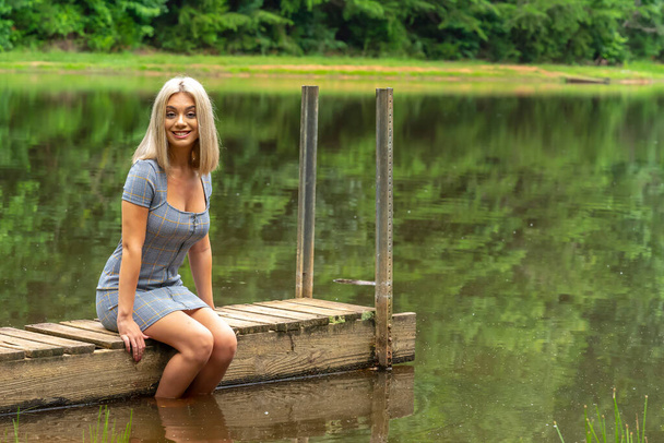 Ein hinreißendes junges blondes Model posiert draußen in einem Sonnenblumenfeld, während es einen Sommertag genießt - Foto, Bild