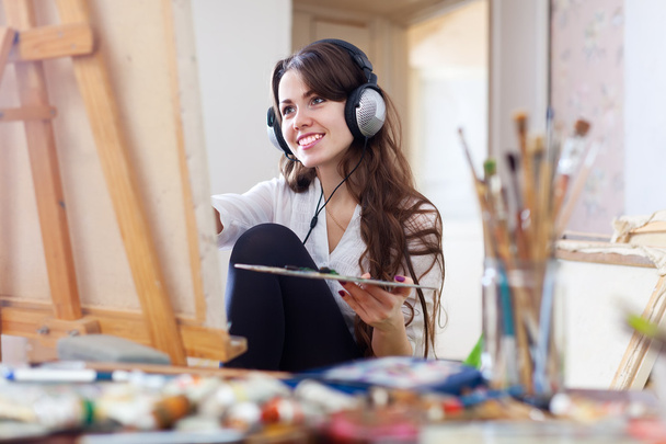 Long-haired girl in headphones paints on canvas - Foto, immagini