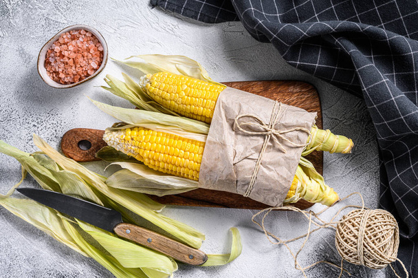 Fresh harvested corn cob on farmer market, local vegetables. Gray background. Top view. - Photo, image